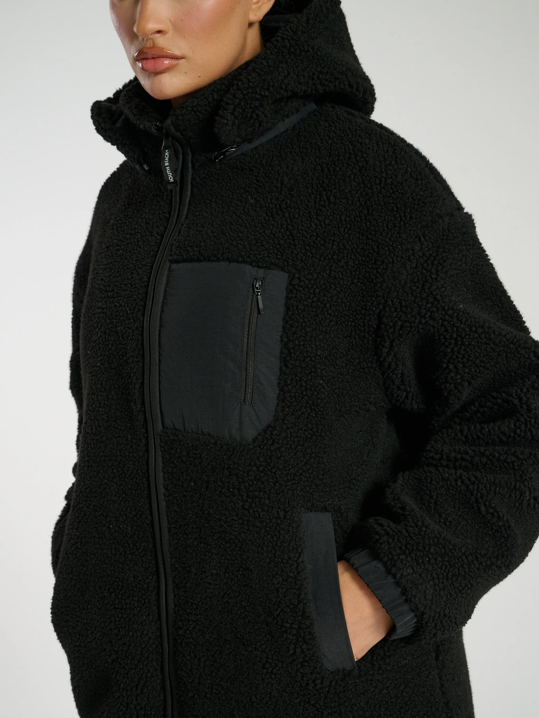 The 'Zip it' hooded midi length teddy fleece coat in black